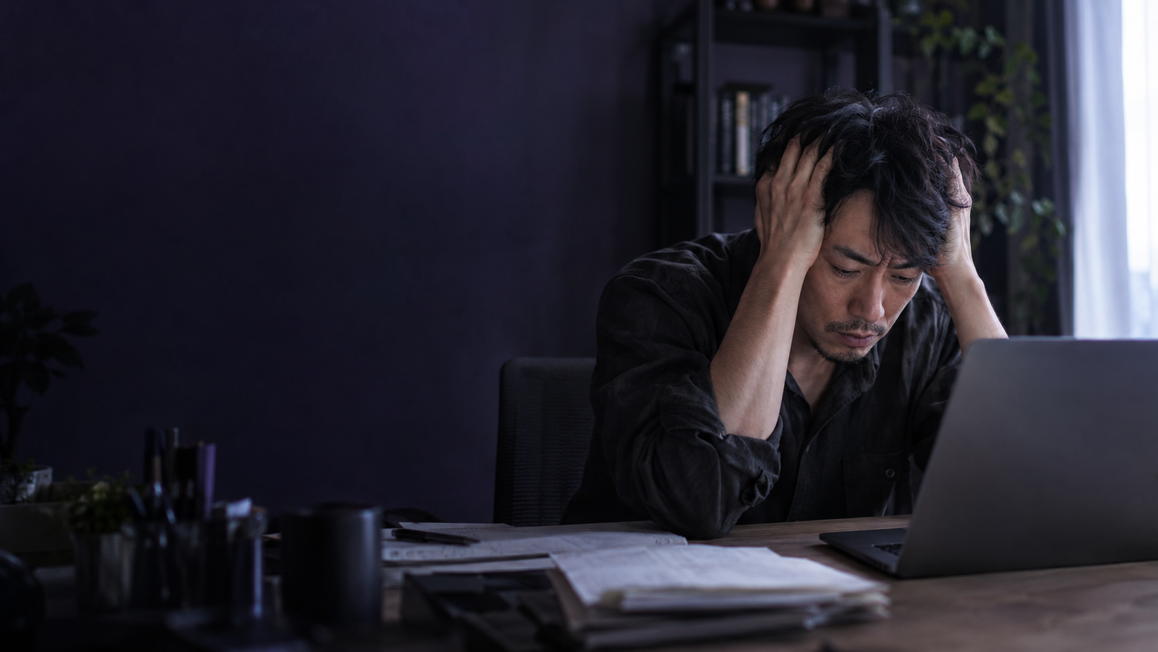 制作した内容を見てもらえず、机で頭を抱える男性の生成写真